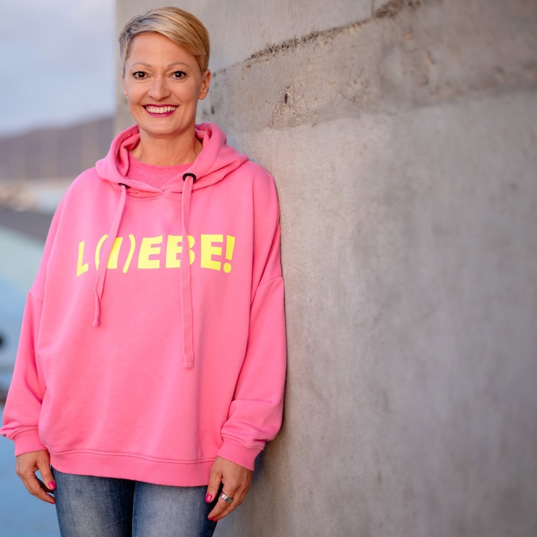 Melanie Mittermaier im pinken Hoodie mit Aufdruck Liebe, Affärenmanagerin für Paarberatung bei Beziehungskrise, Affäre beenden und Fremdverliebt.